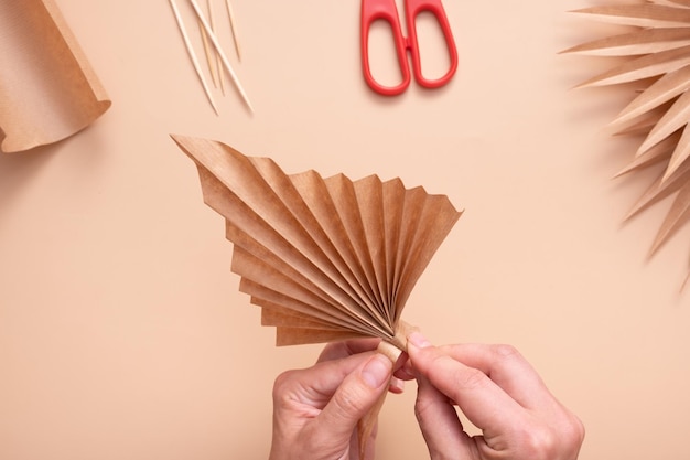 De stam van het blad omwikkelen met een gelijmde strook papier Creatief handwerk om tropische bladeren te maken Masterclass
