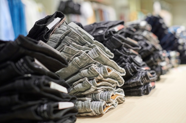 De stapel van denimjeans op houten tafel bovenop in kledingwinkel in modern winkelcentrum