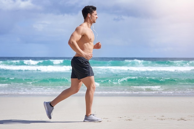 De stappen naar fitness zetten Shot van een knappe jongeman die jogt op het strand