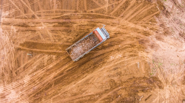 De stortplaatsvrachtwagen maakt grond op de bouwwerf leeg. luchtfoto