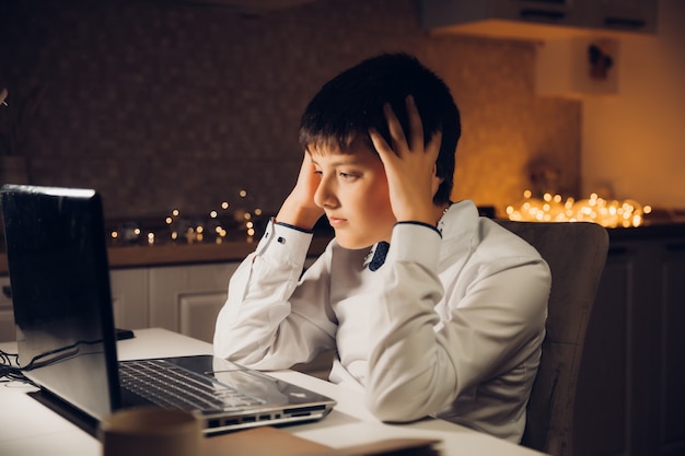 De student bereidt zich 's avonds laat voor op het examen. een tiener zit achter een laptop en is laat in de avond verloofd.