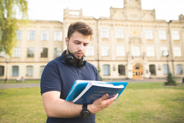 De student staat op de achtergrond van de universiteit en leest het boek.