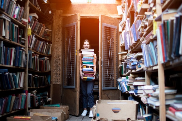 De studente houdt een grote stapel boeken