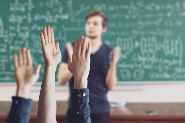 De studenten op school met opgeheven handen in de klas leren samen