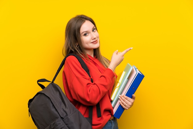 De studentenmeisje van de tiener over gele wijzende vinger aan de kant