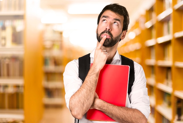 De studentenmens die defocused bibliotheek denken