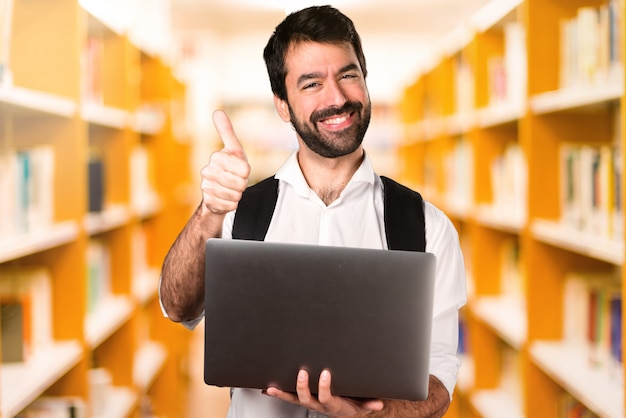 De studentenmens met laptop defocused bibliotheek