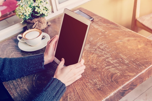 de tablet van de handvrouw het spelen in koffiewinkel met uitstekende toon.