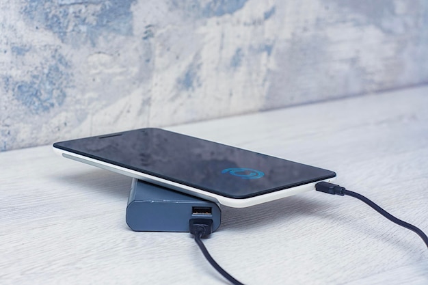 Foto de tablet wordt opgeladen met een draagbare oplader op een houten tafel