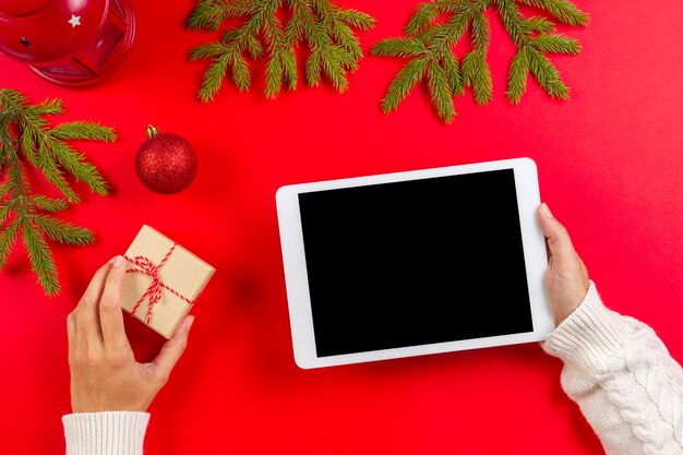 De tabletcomputer in vrouw overhandigt rood met decoratie van Kerstmis