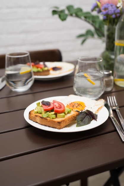 De tafel met ontbijt van sandwiches en gebakken eieren glazen water met citroen