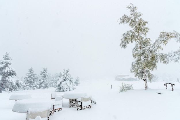 De tafels en stoelen van een restaurant zijn bedekt met zware sneeuw