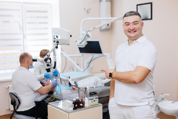 De tandarts is in zijn tandartspraktijk Een tandarts in een wit uniform behandelt de tanden van een patiënt met een tandheelkundige microscoop Tandartspraktijk