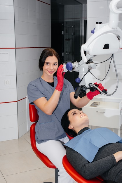 De tandarts kijkt door een microscoop en voert een operatie uit bij de patiënt.