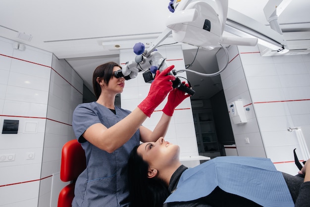 De tandarts kijkt door een microscoop en voert een operatie uit bij de patiënt