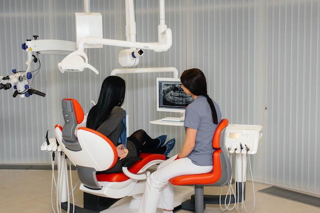 De tandarts laat een foto zien van het gebit van de patiënt en vertelt de noodzakelijke behandeling. Tandheelkunde, gezondheid.