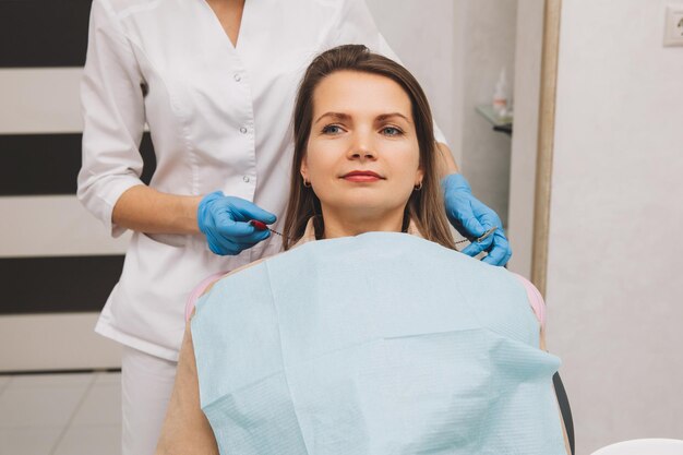 De tandarts legt een servet op de patiënt. vrouw wachten op tandheelkundige behandeling. Behandeling van mondglazuur in de gezondheidszorg.