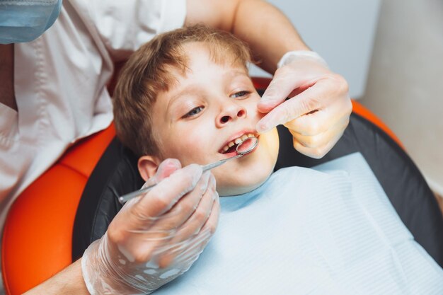 De tandarts onderzoekt de tanden van een jongen van 13 jaar oud in de kliniek pediatrische tandheelkunde