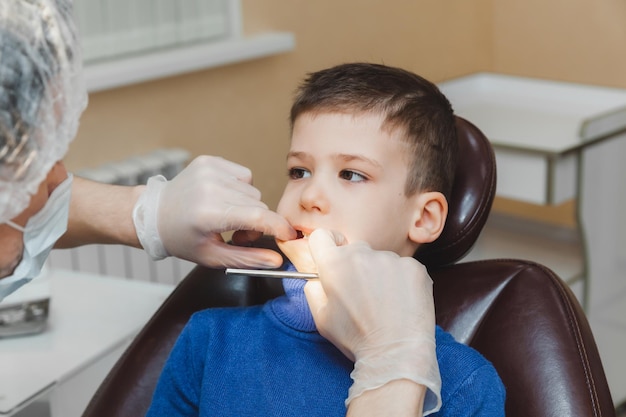 De tandarts onderzoekt de tanden van een kleine jongen, een patiënt in een tandheelkundige kliniek