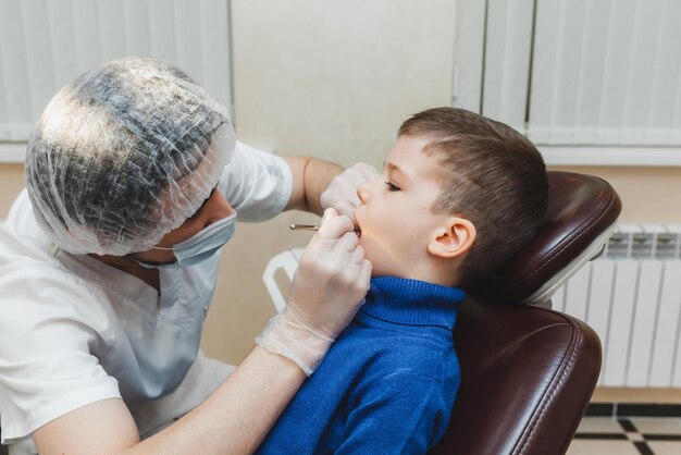 De tandarts onderzoekt de tanden van een kleine jongen, een patiënt in een tandheelkundige kliniek