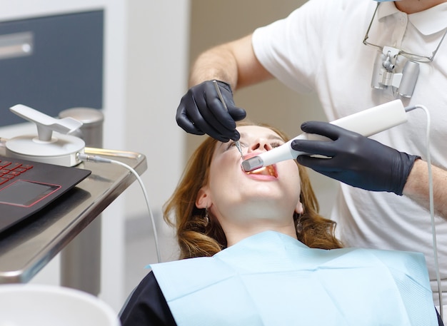 De tandarts scant de tanden van de patiënt met een 3D-scanner.