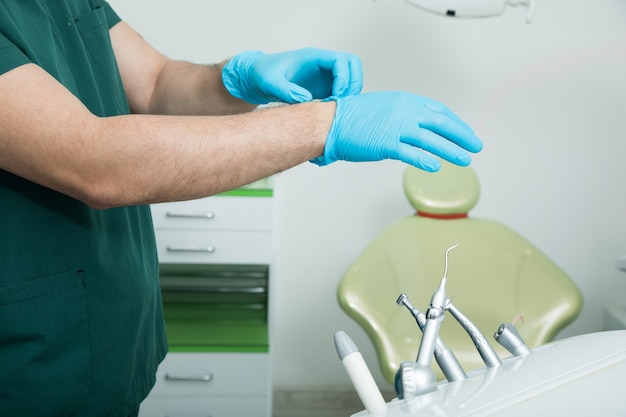 De tandarts trekt voor het werk handschoenen aan