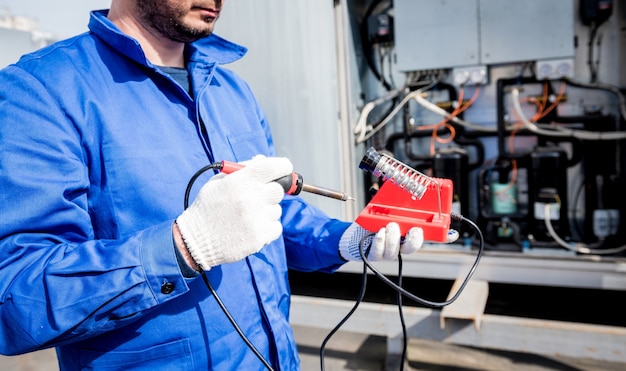 De technicus repareert elektronische temperatuursensoren met een elektronische soldeerbout