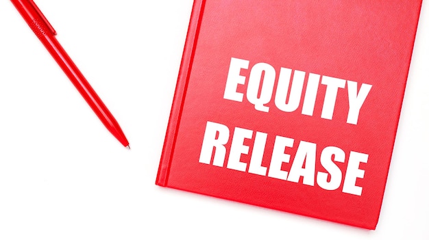 De tekst EQUITY RELEASE is geschreven op een rood notitieblok in de buurt van een rode pen op een witte tafel op kantoor Bedrijfsconcept