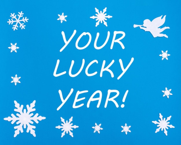 Foto de tekst is uw gelukkig jaar op een blauwe achtergrond met kerstsneeuwvlokken een witte engel