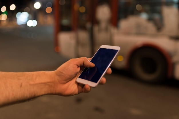 De telefoon van de handholding zwart binnen het knippen met bokeh