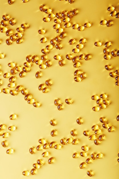 De textuur van de capsules in de schaal met vloeibare vitamine D3 in gouden capsules op volledig scherm