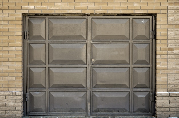 De textuur van een geschilderde metaalpoort van een baksteengarage