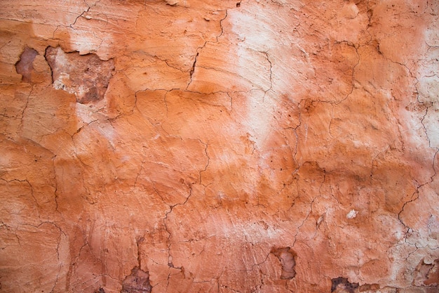 De textuur van een rode betonnen muur met scheuren en krassen kan als achtergrond worden gebruikt