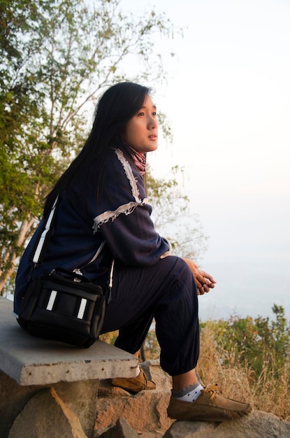 De Thaise vrouw van reizigers zit en poseert voor het nemen van foto's op de top van de phu tok-berg in zonsopgangtijd in Chiang Khan in Loei Thailand