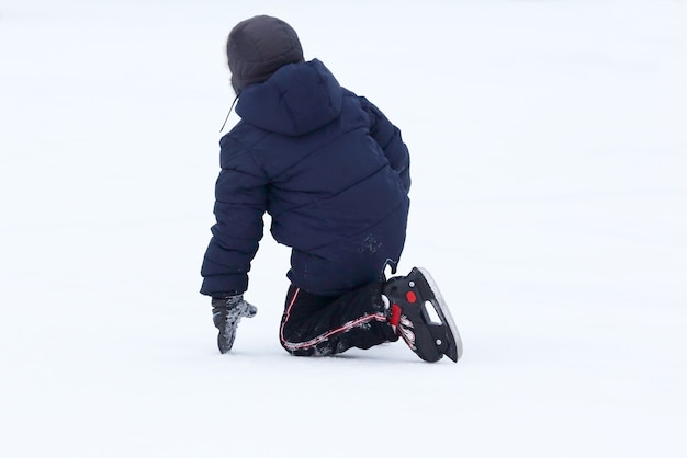 De tiener viel schaatsend op de ijsbaan