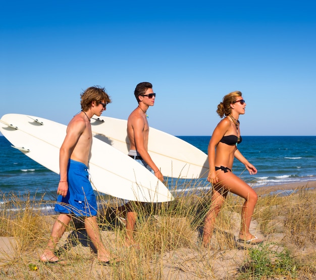 De tienergroep die van Surfer op duin weg aan strand loopt