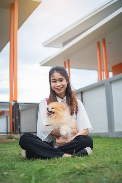 De tienervrouw het spelen met Pomperanian-hond in het huis, Aziatische vrouw, ontspant openlucht
