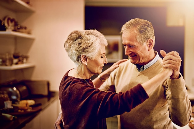 De tijd heeft hen laten zien wat er echt toe doet in het leven Shot van een ouder stel dat met elkaar danst in hun keuken