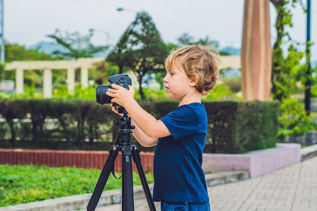 De Toddler jongen maakt foto's op een camera op een statief