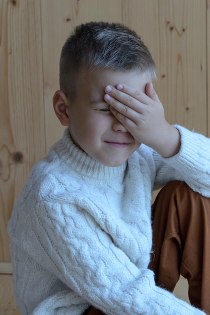 de toekomstige schooljongen bedekte zijn gezicht met zijn hand in verlegenheid