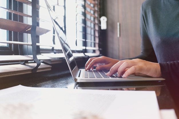 De toevallige bedrijfsvrouw werkt online op laptop die op toetsenbord hand.