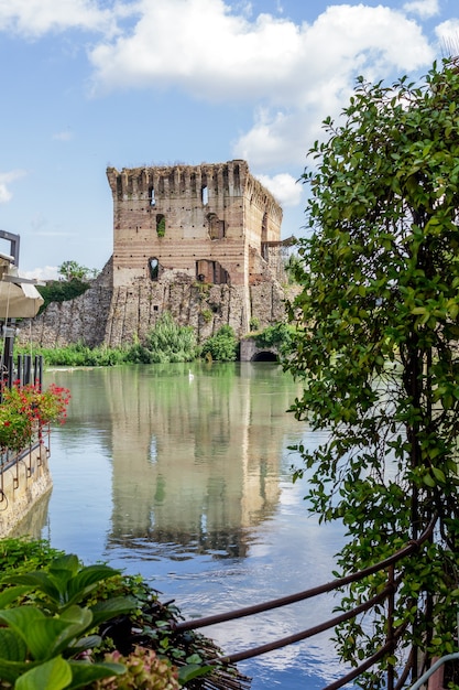 De toren van de muren van Borghetto sul Mincio weerspiegeld in de gladde rivier met de kleuren van de zomer