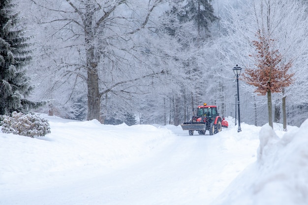 De tractor maakt weg van sneeuw in de winter schoon