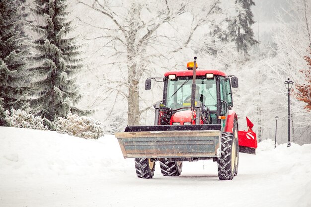De tractor maakt weg van sneeuw in de winter schoon