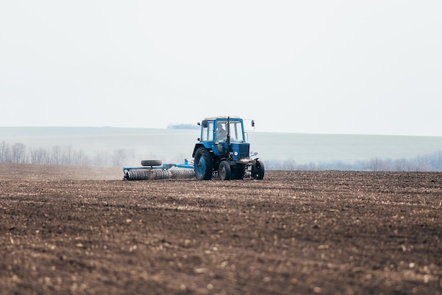 De tractor verwerkt het veld in de voorjaarsoogst tijdens het zaaien van tarwe- en graangewassenxA