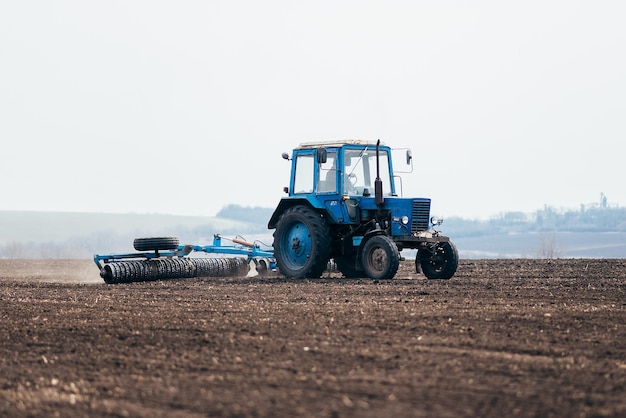 De tractor verwerkt het veld in de voorjaarsoogst tijdens het zaaien van tarwe- en graangewassenxA