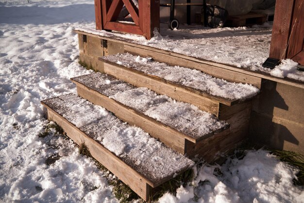 De treden van houten trappen zijn bedekt met sneeuw tijdens een sneeuwval Afdaling naar het erf van het huis Koude dag in het dorp