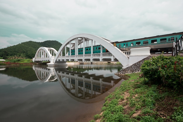 De trein steekt de witte brug over met een prachtig uitzicht op de bergen