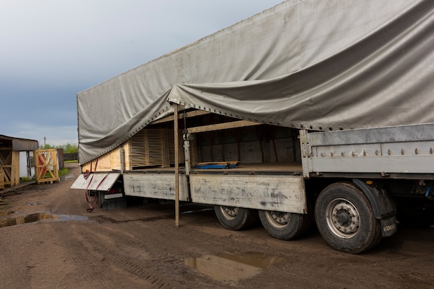 De trekker laadt planken, hout uit het magazijn voor afgewerkte producten in de container van de vrachtwagen. hoge kwaliteit foto