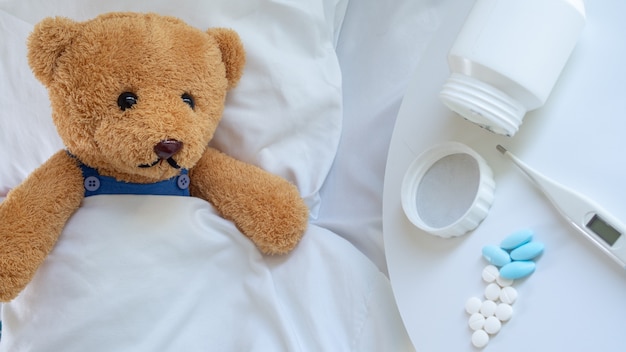 De trieste teddybeer had hoofdpijn en koorts en lag ziek in bed